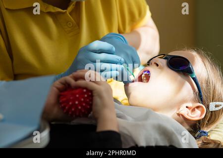 Zahnplaque rosa und lila. Baby-Mundspülung. Zahnarztbesuch. Zähne vor und nach dem Putzen und Aufhellen in einem Foto. Vorbeugend Stockfoto