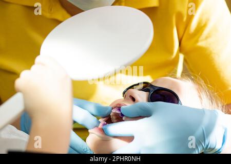 Zahnplaque rosa und lila. Baby-Mundspülung. Zahnarztbesuch. Zähne vor und nach dem Putzen und Aufhellen in einem Foto. Vorbeugend Stockfoto