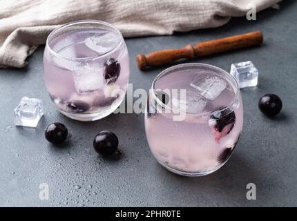 Brasilianischer jabuticaba caipirinha in Gläsern mit Eis und Früchten auf Steinhintergrund. Stockfoto