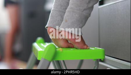 Ein Kind, das auf Zehenspitzen steht und in die Küche greift. Ein Jahr alte Baby-Zehennaht Stockfoto