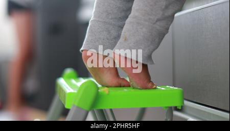 Ein Kind, das auf Zehenspitzen steht und in die Küche greift. Ein Jahr alte Baby-Zehennaht Stockfoto