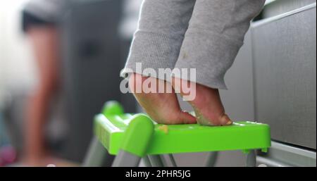 Ein Kind, das auf Zehenspitzen steht und in die Küche greift. Ein Jahr alte Baby-Zehennaht Stockfoto