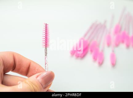 Nahaufnahme von pinkfarbenen Bürsten zum Kämmen von Wimpern und Augenbrauen, Werkzeug für die Behandlung im Schönheitssalon. Stockfoto