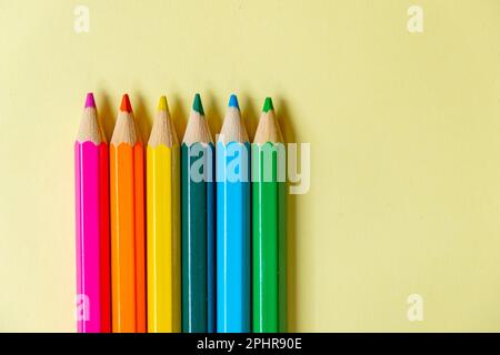 Mehrere Buntstifte auf pastellgelbem Hintergrund. Stockfoto