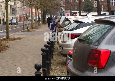 Posen, Polen - 20. Januar 2023: Autos parken auf der Straße, Menschen gehen auf dem Bürgersteig entlang. Stockfoto