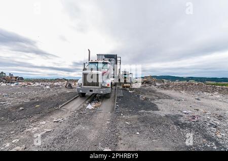 Großes Bohrfahrzeug mit Auflieger auf Anhänger-Kipper auf einer aktiven Deponie. Stockfoto