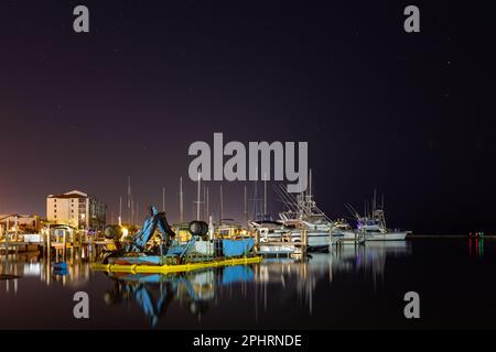 Ein Bild der Raumküste in Titusville bei Nacht, lange ausgesetzt. Die Skyline der Boote und ihre Reflexion im Wasser Stockfoto