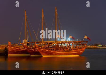 Traditionelle Dhows, die nachts in Doha in Katar vor Anker gehen. Stockfoto