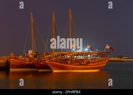 Traditionelle Dhows, die nachts in Doha in Katar vor Anker gehen. Stockfoto