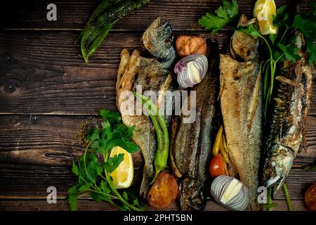 Köstliche gegrillte Makrelen, Forellen, Wolfsbarsch und Seebrassen mit Zitronenscheiben und frischen Kräutern. Perfekt für Grill- und Grillprodukte oder Restaurantthemen. Stockfoto