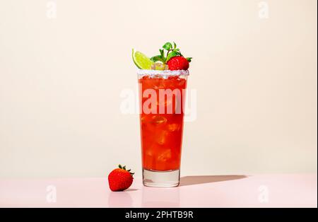 Paloma alkoholisches Cocktailgetränk mit Tequila, Grapefruit und Limettensaft, Erdbeeren, Minze und Eis im Glas mit salzhaltigem Rand. Beige rosa Vanille Backgr Stockfoto