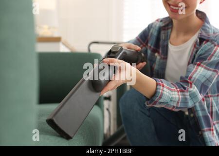 Junge Frau saugt Sofa im Wohnzimmer ab, schließt Stockfoto