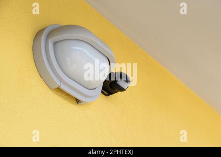 Moderne Straßenlampe an der gelben Wand des Gebäudes Stockfoto