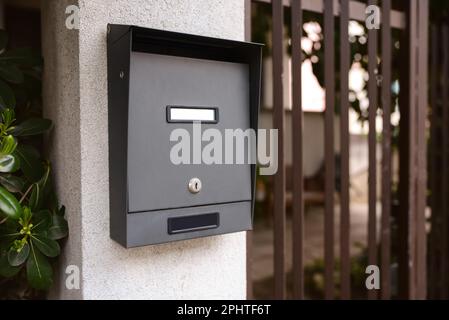 Schwarzer Metallpostkasten im Freien in der Nähe des Eingangs am Frühlingstag Stockfoto