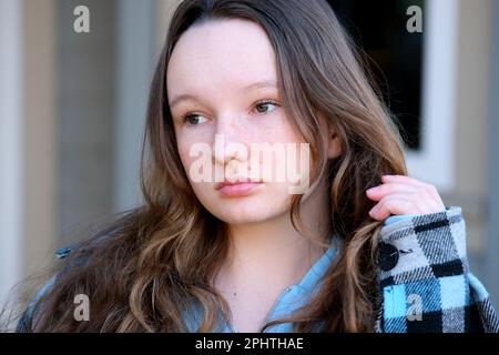 Nahaufnahme eines hübschen, lachenden jungen gemischten Rennmädchens mit lockigem Haar, das sich im Wind bewegt. Glückliche, wunderschöne britische, birassische junge Frau mit dem Denkmal der weißen Bögen im Hintergrund Stockfoto