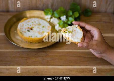 Halten Sie ein Stück von Ghewar oder ghevar in der Hand, eine traditionelle Süßigkeit von rajasthan. Es besteht aus Milch, Mehl, Ghee und Zucker. Trockenfrüchte und Malai c Stockfoto