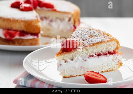 Ein Stück Victoria Kekskuchen mit Schlagsahne, Marmelade und frischen Erdbeeren. Stockfoto