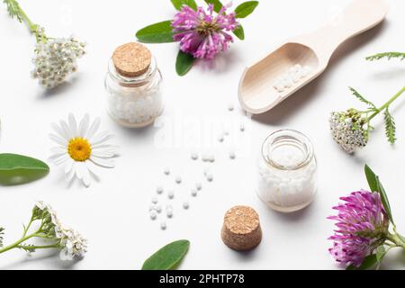 Zusammensetzung von homöopathischen Arzneimitteln und Heilpflanzen auf einem weißen Tisch. Stockfoto