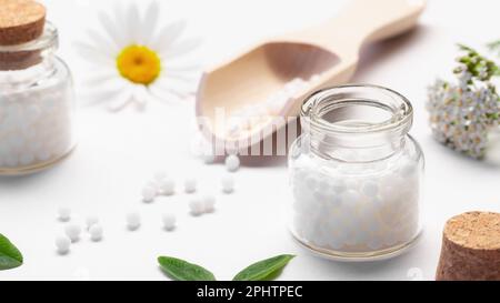 Zusammensetzung von homöopathischen Arzneimitteln und Heilpflanzen auf einem weißen Tisch. Stockfoto