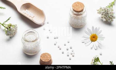 Zusammensetzung von homöopathischen Arzneimitteln und Heilpflanzen auf einem weißen Tisch. Stockfoto