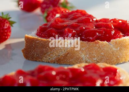 Toast mit Erdbeermarmelade auf dem Tisch. Stockfoto