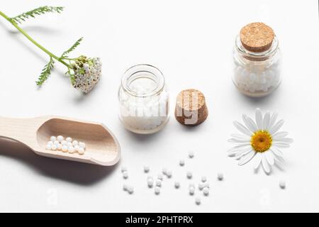 Zusammensetzung von homöopathischen Arzneimitteln und Heilpflanzen auf einem weißen Tisch. Stockfoto