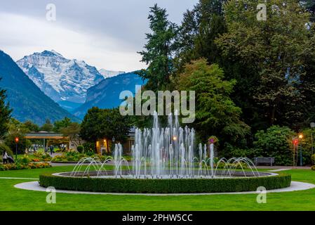 Blick auf den Sonnenuntergang über den Brunnen im Kasino Interlaken in der Schweiz. Stockfoto