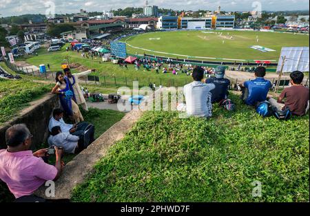 Ein frisch verheiratetes Paar steht unter Zuschauern im alten holländischen Fort in Galle in Sri Lanka. Sie sehen sich ein Cricketspiel an. Stockfoto