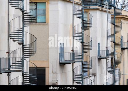 Außen spiralförmige Feuertreppen aus Metall, die zu Notausgängen an der Rückseite eines Gebäudes führen Stockfoto