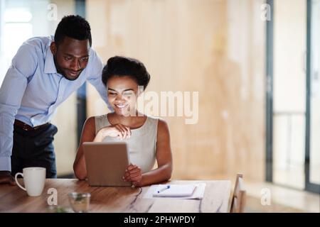 Erfolg mit nur einem Tastendruck aufbauen. Kollegen, die ein digitales Tablet zusammen in einem Büro verwenden. Stockfoto