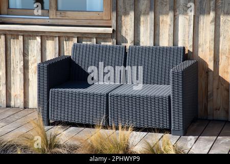 Leerer Stuhl, graue Sitzdekoration, Außenterrasse, Gartenbank, Sofa, Holzfassade, Terrasse Stockfoto