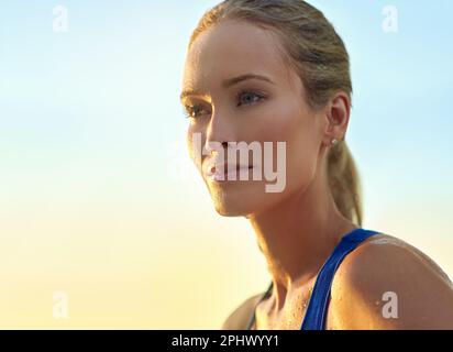 Immer nach vorne schauen. Eine sportliche junge Frau, die draußen steht. Stockfoto