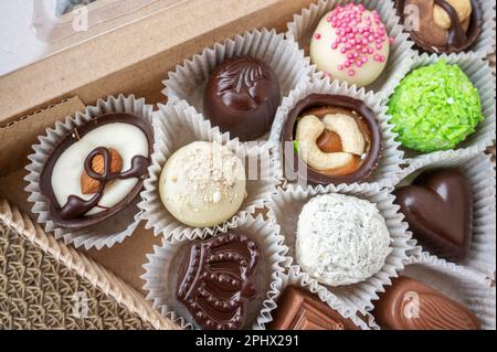 Verschiedene handgemachte Süßigkeiten, Schweizer Pralinen in Geschenkbox, verschiedene luxuriöse Pralinen aus dunkler und milchhaltiger Bio-Schokolade, süßes Dessertessen als Urlaub Stockfoto