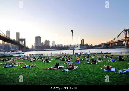 Yoga-Session bei Sonnenuntergang im Brooklyn Bridge Park in New York City, NY, USA. Stockfoto