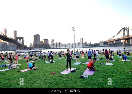 Yoga-Session bei Sonnenuntergang im Brooklyn Bridge Park in New York City, NY, USA. Stockfoto