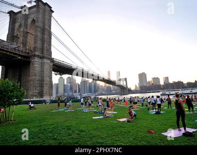 Yoga-Session bei Sonnenuntergang im Brooklyn Bridge Park in New York City, NY, USA. Stockfoto