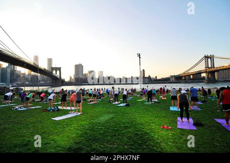 Yoga-Session bei Sonnenuntergang im Brooklyn Bridge Park in New York City, NY, USA. Stockfoto