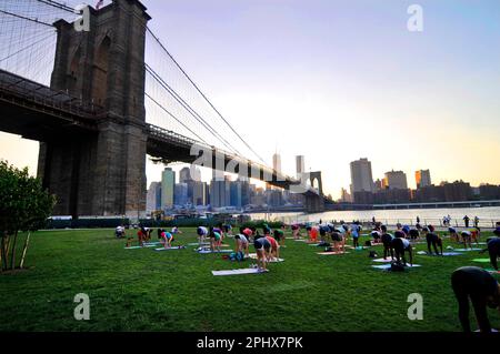 Yoga-Session bei Sonnenuntergang im Brooklyn Bridge Park in New York City, NY, USA. Stockfoto