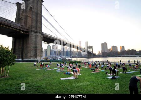 Yoga-Session bei Sonnenuntergang im Brooklyn Bridge Park in New York City, NY, USA. Stockfoto