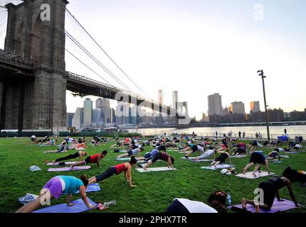 Yoga-Session bei Sonnenuntergang im Brooklyn Bridge Park in New York City, NY, USA. Stockfoto