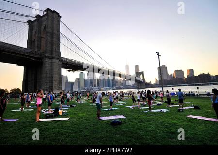 Yoga-Session bei Sonnenuntergang im Brooklyn Bridge Park in New York City, NY, USA. Stockfoto