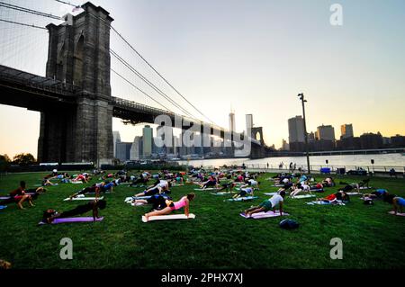 Yoga-Session bei Sonnenuntergang im Brooklyn Bridge Park in New York City, NY, USA. Stockfoto