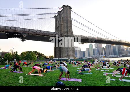 Yoga-Session bei Sonnenuntergang im Brooklyn Bridge Park in New York City, NY, USA. Stockfoto