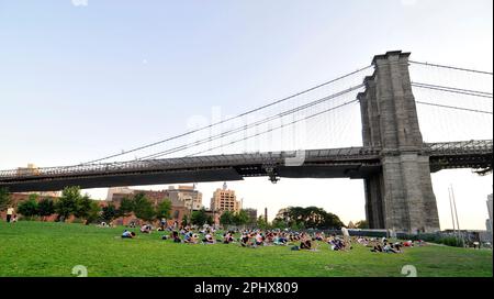 Yoga-Session bei Sonnenuntergang im Brooklyn Bridge Park in New York City, NY, USA. Stockfoto