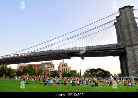 Yoga-Session bei Sonnenuntergang im Brooklyn Bridge Park in New York City, NY, USA. Stockfoto