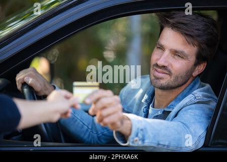 Männlicher Fahrer bezahlt per Karte Stockfoto