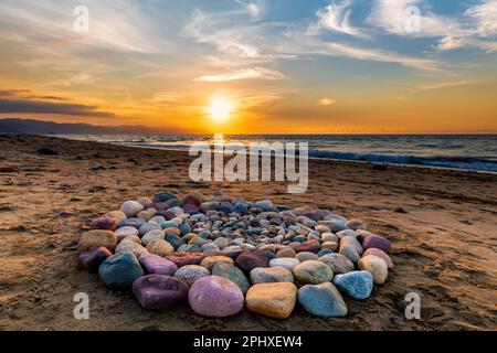 Während des Sonnenuntergangs am Strand werden heilige Ritualsteine für spirituelle Zeremonien in Einem Kreis angeordnet Stockfoto