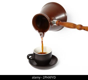 Mann, der Kaffee in eine Tasse gießt, isolierter weißer Hintergrund. Clay Cezve für die Kaffeezubereitung in der Hand Stockfoto