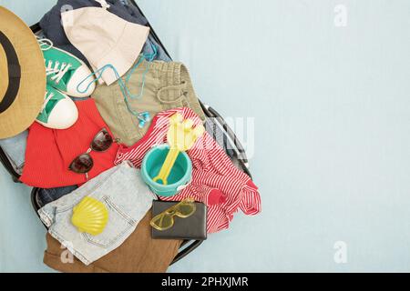 Offener Koffer und Gepäck mit verschiedenen eingepackten Kleidungsstücken. Reisekonzept. Draufsicht, Kopierbereich Stockfoto