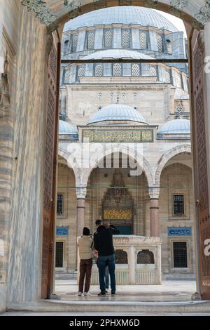 Ein Touristenpaar im Hof der Suleymaniye Moschee. Reisen Sie nach Istanbul, vertikales Hintergrundfoto. Istanbul Turkiye - 12.23.2022 Stockfoto